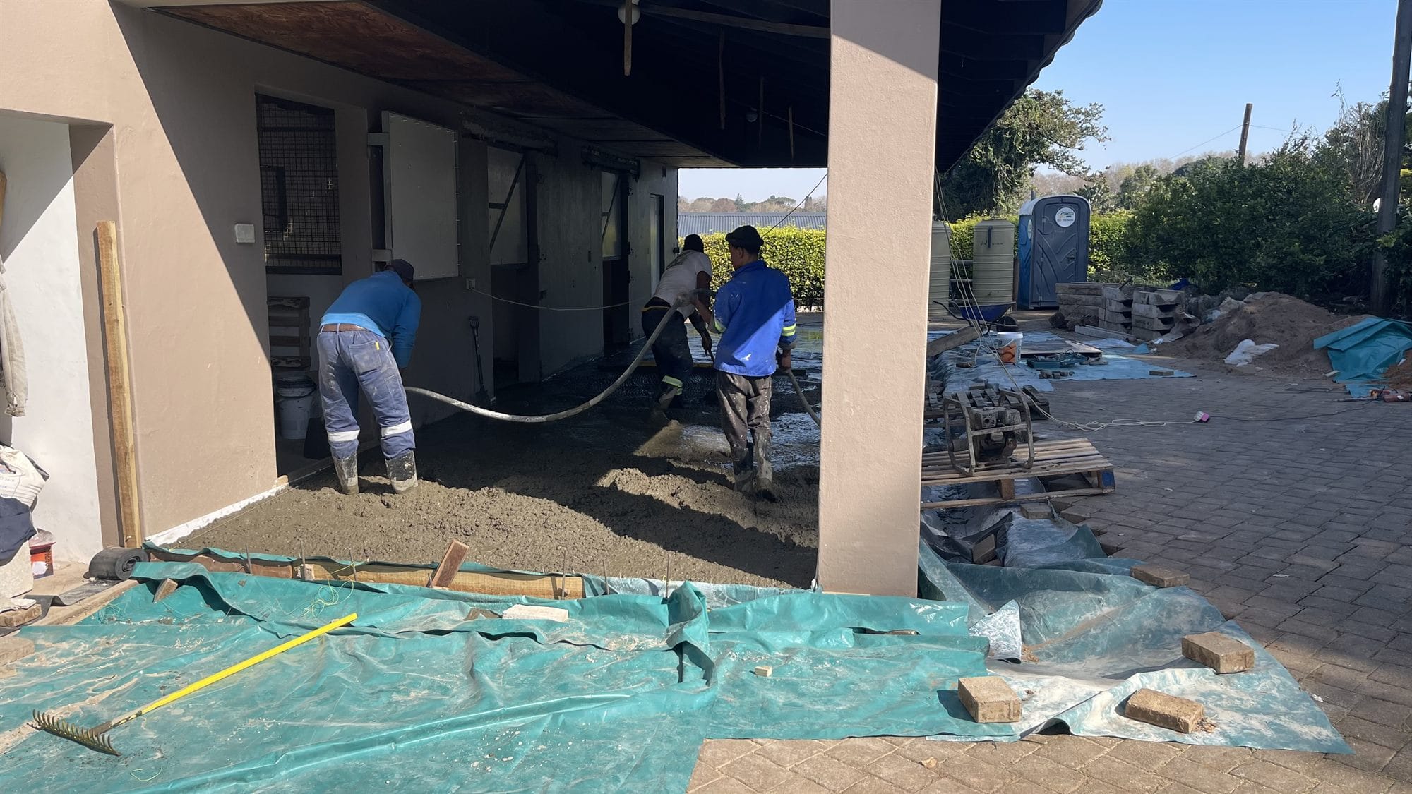 Three of the Star Painters team screeding a freshly poured concrete slab, in branded workwear and hi-vis